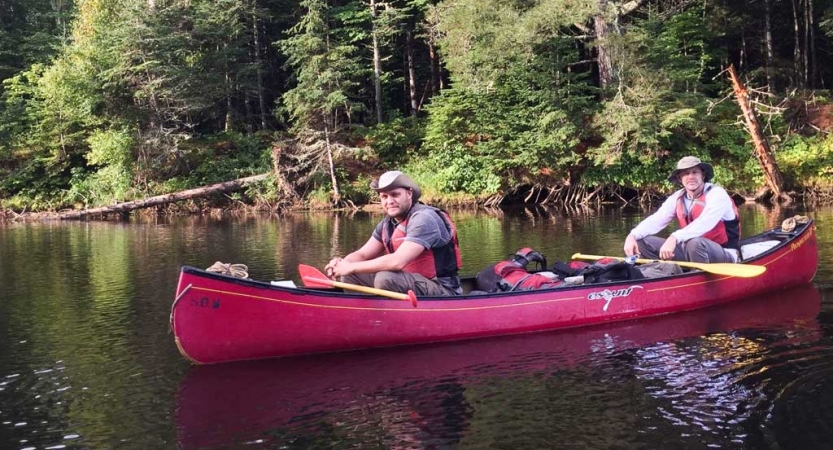 veterans smile at the camera while sitting in a canoe on an outward bound expedition